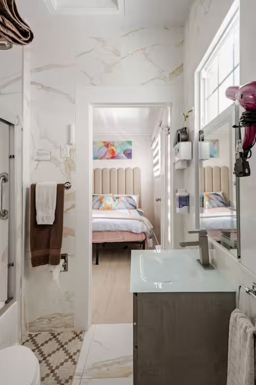 Bathroom #2  Jack and Jill, with dual access from two bedrooms. Fully tiled from ceiling to floor to minimize dust buildup, featuring a sleek wall-mounted vanity, towel warmer, and smart mirror with anti-fog function for comfort and functionality.
