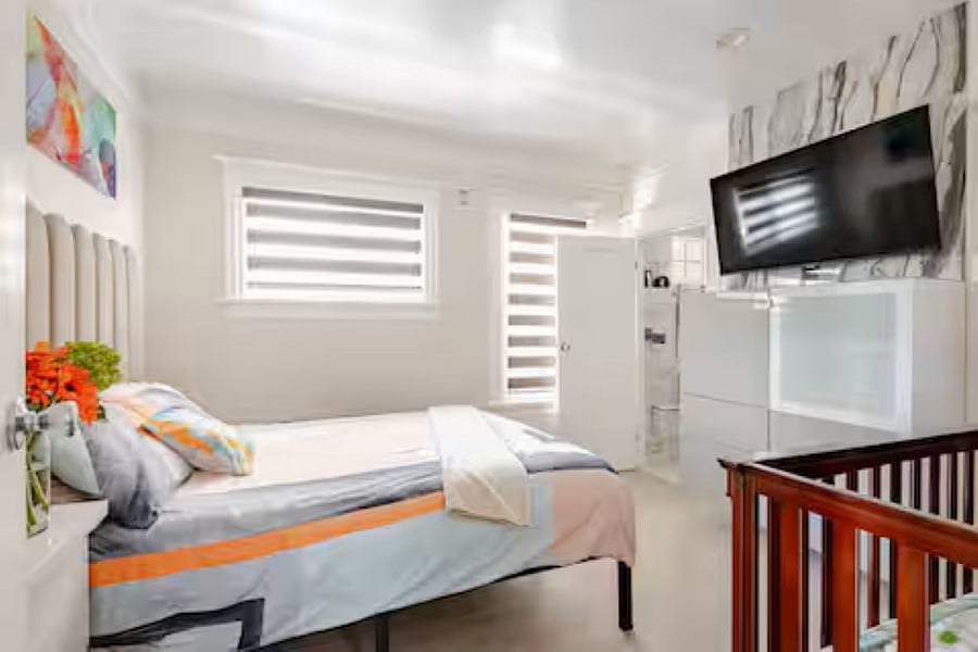 Bedroom #3(Queen bed): The dramatic TV feature wall anchors the room with style, while the smart zebra shade balances the bold design with soft, natural light. A wall-mounted smart TV and sleek dresser offer a striking yet functional centerpiece.