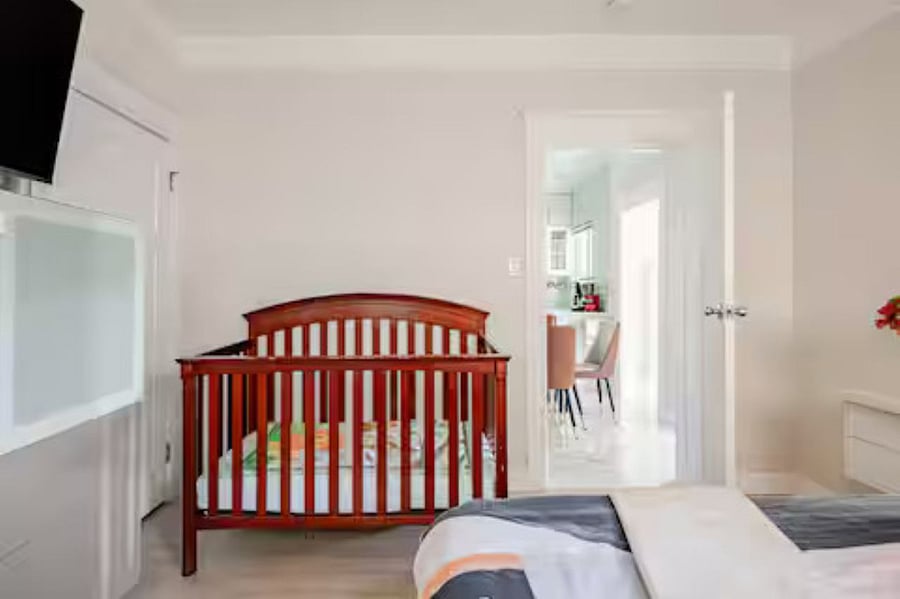 Bedroom #3( Queen bed and crib): The dramatic accent wall showcases a wall-mounted smart TV and a modern floating dresser, while a thoughtfully provided infant crib ensures a comfortable stay for even your littlest guest.