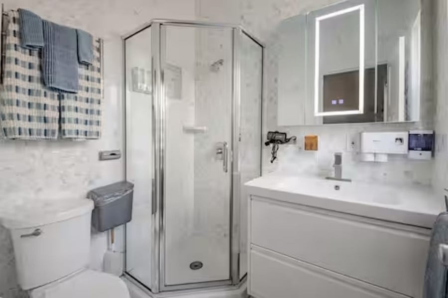 Bath #1: Sophisticated and urban, this bathroom boasts floor-to-ceiling tile for a sleek, modern vibe. A floating vanity, integrated sink, towel warmer, and automatic soap dispenser bring form and function together in a thoughtfully curated space.
