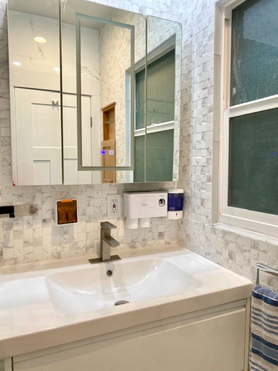Bath #1: Enjoy a spa-like setting with a smart LED lighted mirror, an automatic hand soap dispenser, wall-mounted cups, and a sleek floating integrated sink that enhances the bathrooms clean, modern aesthetic.