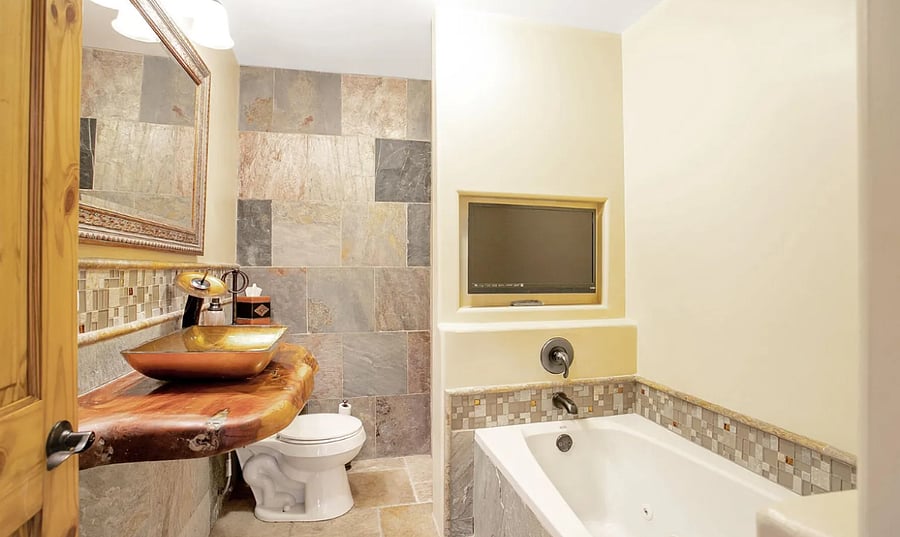 Hallway bathroom with tub and storage