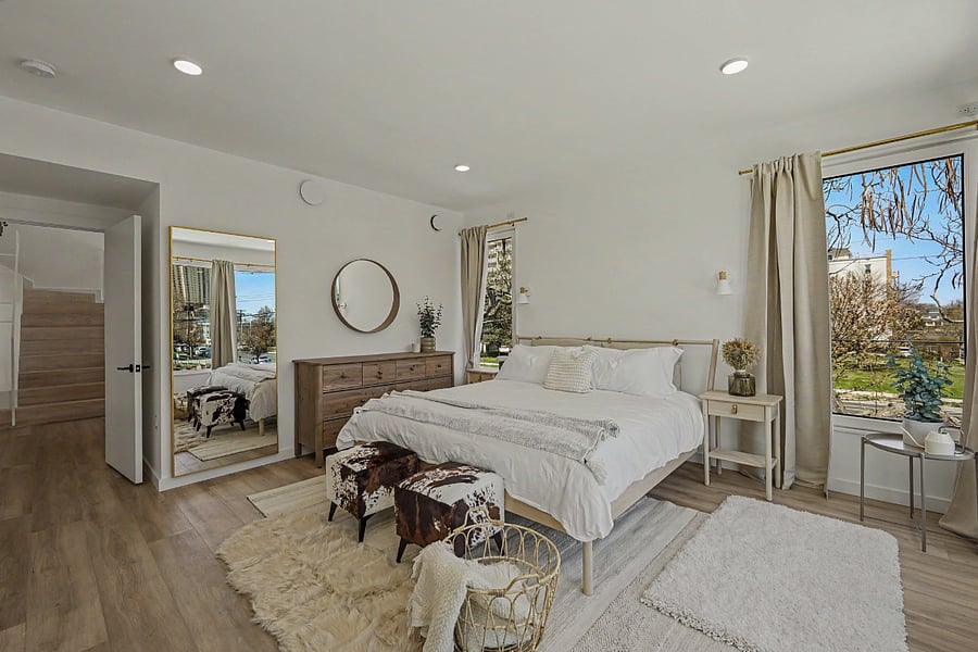 The primary king at the back of the house. Own en-suite, round mirror that catches the morning light, curtains that close against the street. Quiet enough to hear the block breathe.