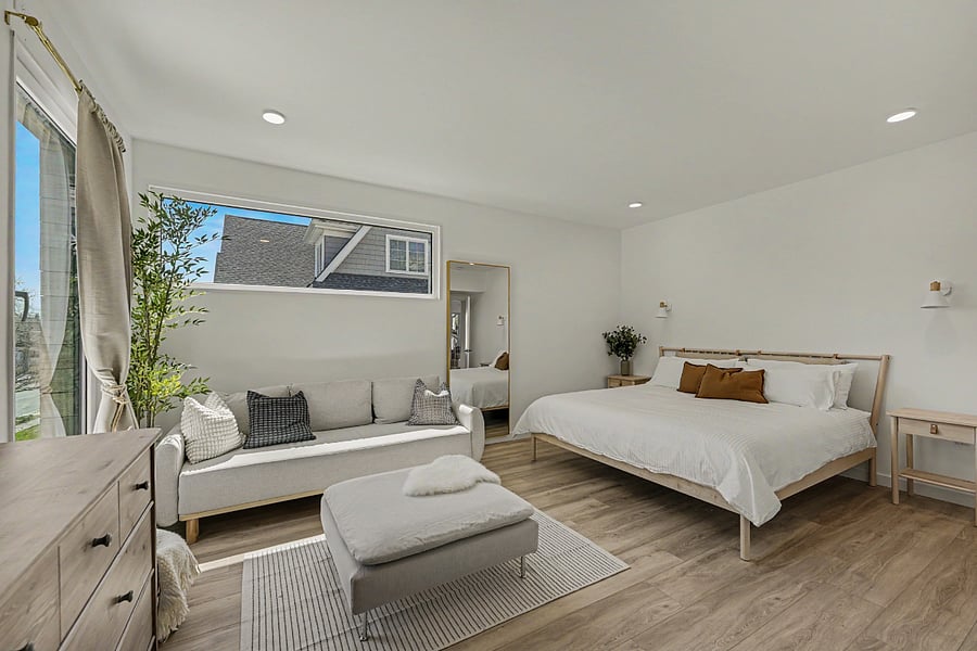 The secondary king suite. En-suite bath, generous light from the corner windows, a small sofa at the foot of the bed for the book you'll read before sleep.