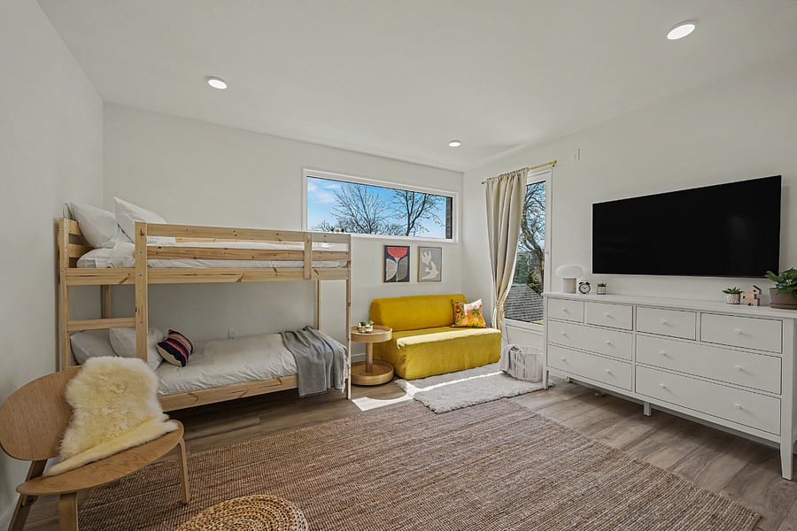 The bunk room twin-over-twin, yellow reading sofa, dresser and TV. Set up for kids without feeling like a kids' room.