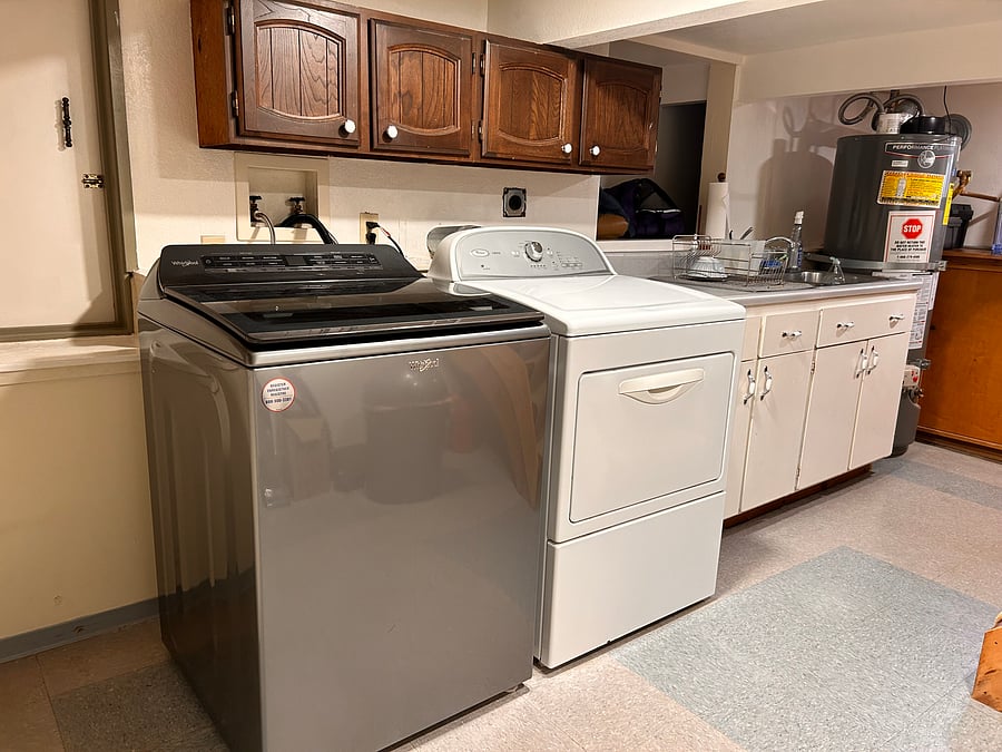 Shared laundry space with newer Whirlpool washer, and dryer. A private sink cabinet for meal cleanup.