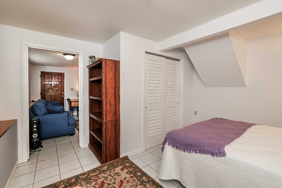 Bedroom with large closet and wall mounted TV next to the bookcase