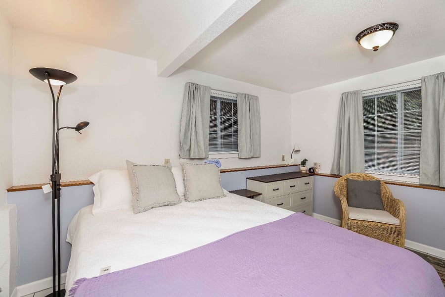 Bedroom showing blackout curtains, ample dresser storage, wicker sitting chair