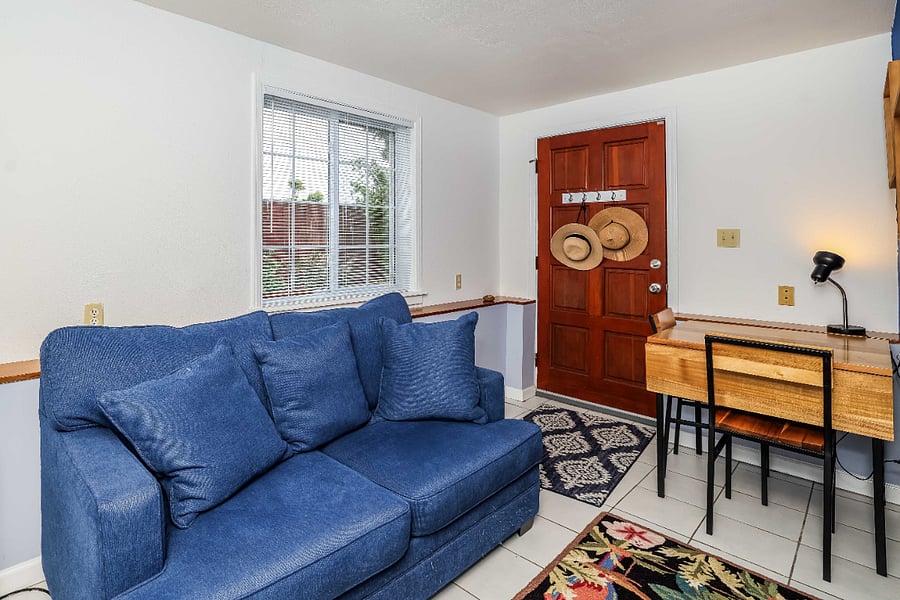 Loveseat and table and chairs in the light filled foyer with private entrance. Optionally, the loveseat can be moved to the bedroom and the adjustable height work desk can take its place in the foyer.