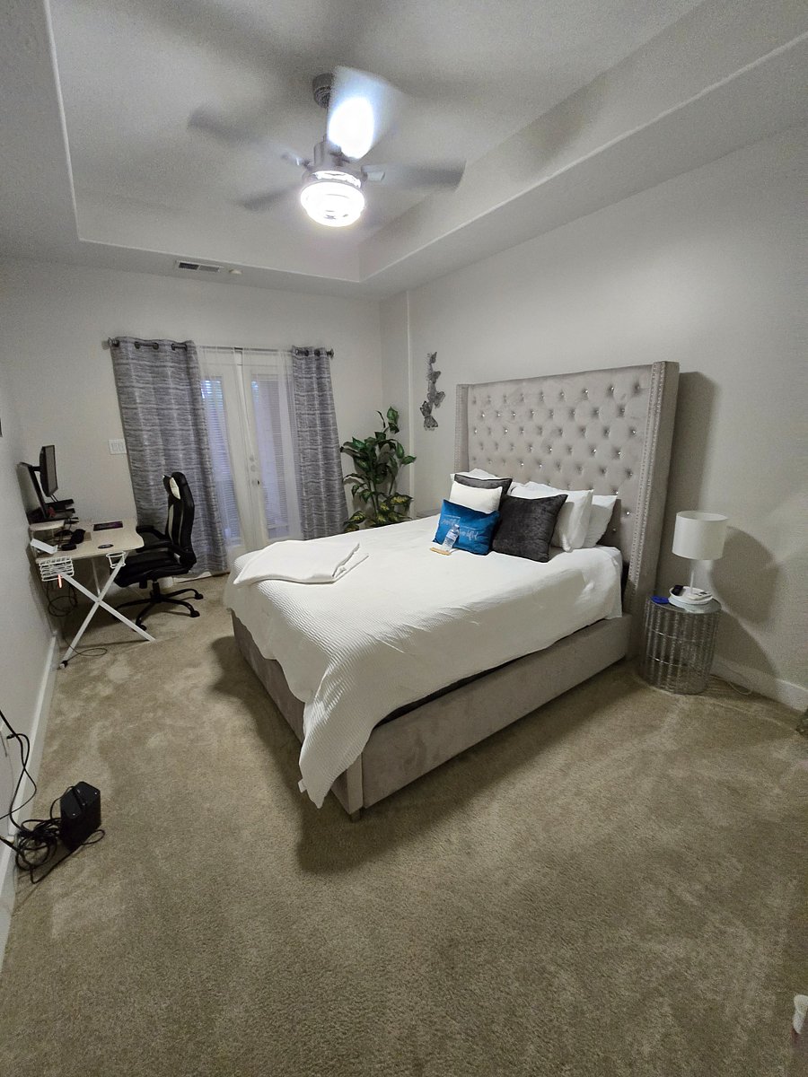 Comfortable and well-appointed second bedroom featuring a plush bed, dedicated workspace, and natural light. Enjoy direct access to the private backyard patio, creating a perfect blend of indoor comfort and outdoor relaxation, ideal for unwinding or working from home.