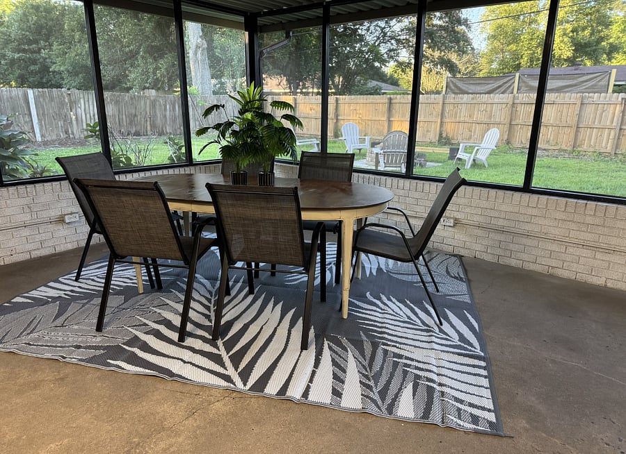Relax on the screened-in patio with comfortable seating, a 55-inch Smart TV, and views of the backyard lounge area with a firepit.