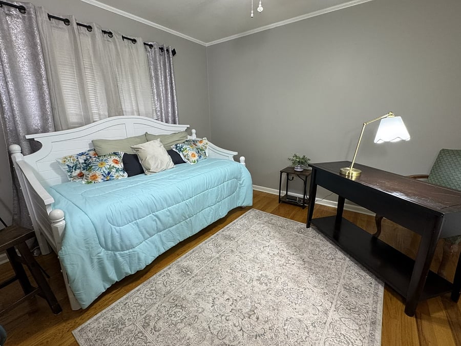 Third bedroom is a flex room with a daybed, a chest of drawers, and a desk with blackout curtains