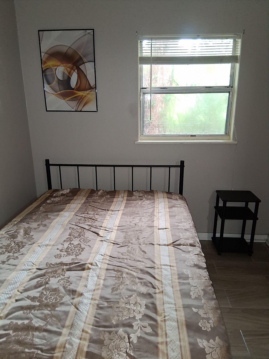 Private bedroom with a full bed, window with blinds, nightstand and workstation with chair.