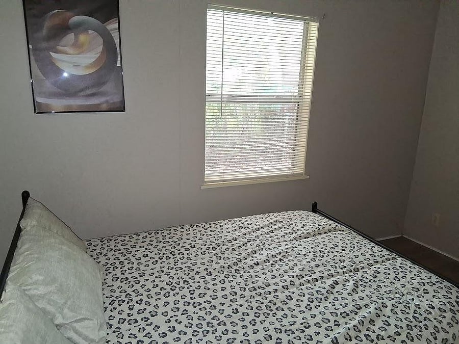 Private bedroom with a furnished bed setup, window blinds for light control, and neutral walls for easy personalization.