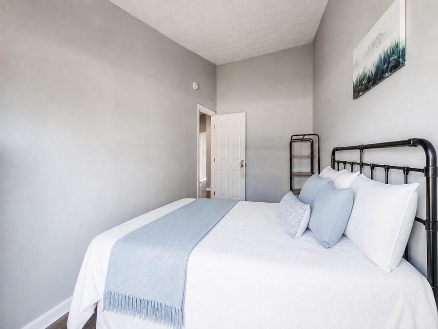 Furnished bedroom with a full-size bed, tall ceilings, and neutral finishes, offering a comfortable space to unwind.