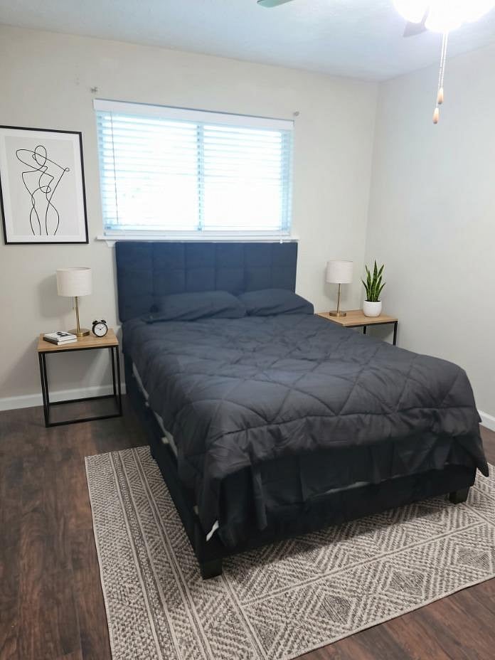 Furnished bedroom with a full bed, bedside tables and lamps, plus a window with blinds for privacy and natural light.