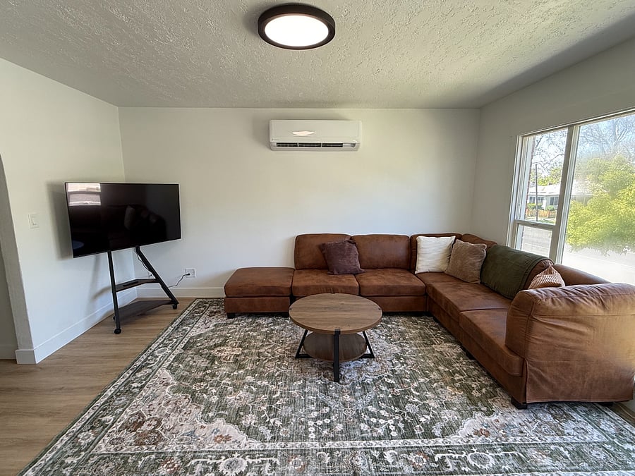 Bright and comfortable living room featuring large windows overlooking 25th Street with mountain views in the background.