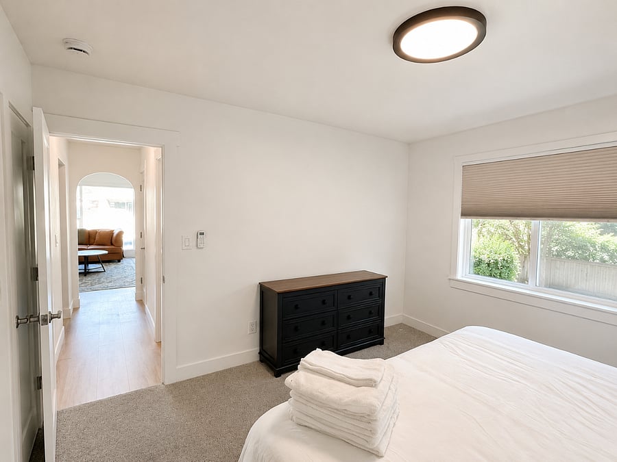 Bright and comfortable bedroom featuring a cozy bed, blackout cellular shades for privacy and better sleep, and a spacious dresser for storage.
