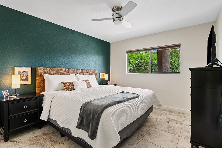 Bedroom 2 is located on the opposite side of the primary for added privacy and features a stylish king bed, cozy accents, TV, and peaceful greenery views.
