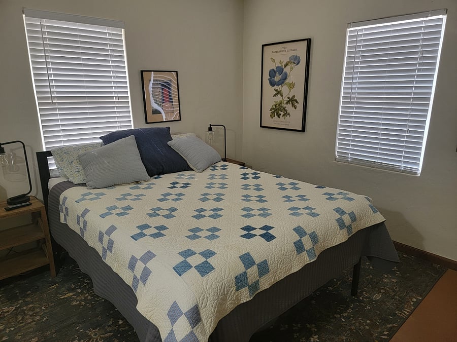 Queen sized bed, smart tv, small desk for laptop use, plus adjoining room with shelves and a printer.