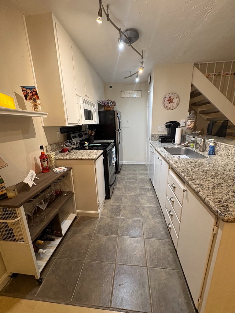 Full kitchen with plenty of cabinet space- Fully stocked with dishes, utensils, pots, and pans-Full size refrigerator, microwave, stove, oven, bar cart, and garbage disposal