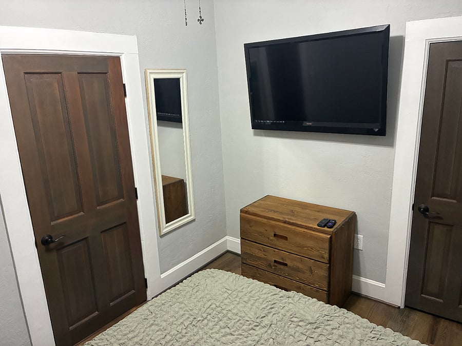 Furnished bedroom with full bed, dresser, lamp, and 45" Roku TV.