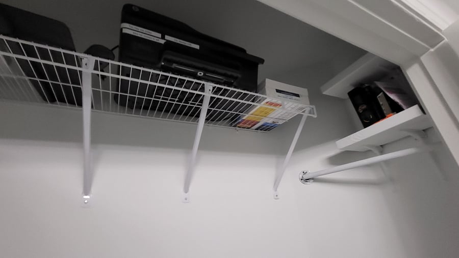 Office supplies and Printer at the top of the closet. Pillow and linens on lower shelf.