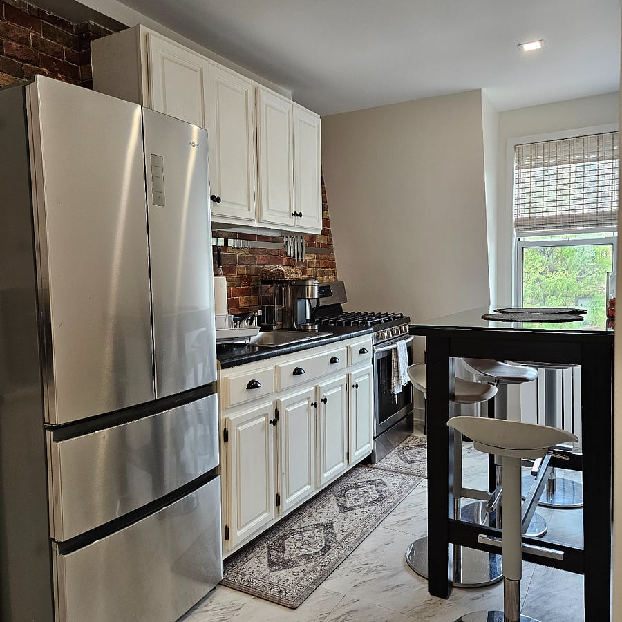 Fully equipped kitchen with full-size fridge, built-in pantry cabinet, and dining table for four