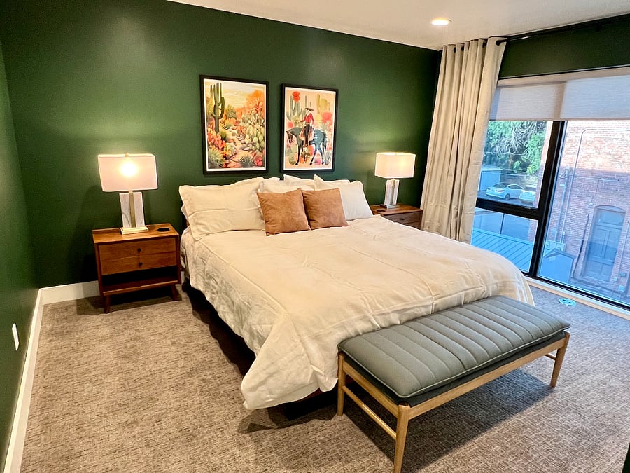 Large bedroom with king size bed, floor to ceiling windows with shades and blackout curtains. Room has two large closets and an en-suite bathroom.
