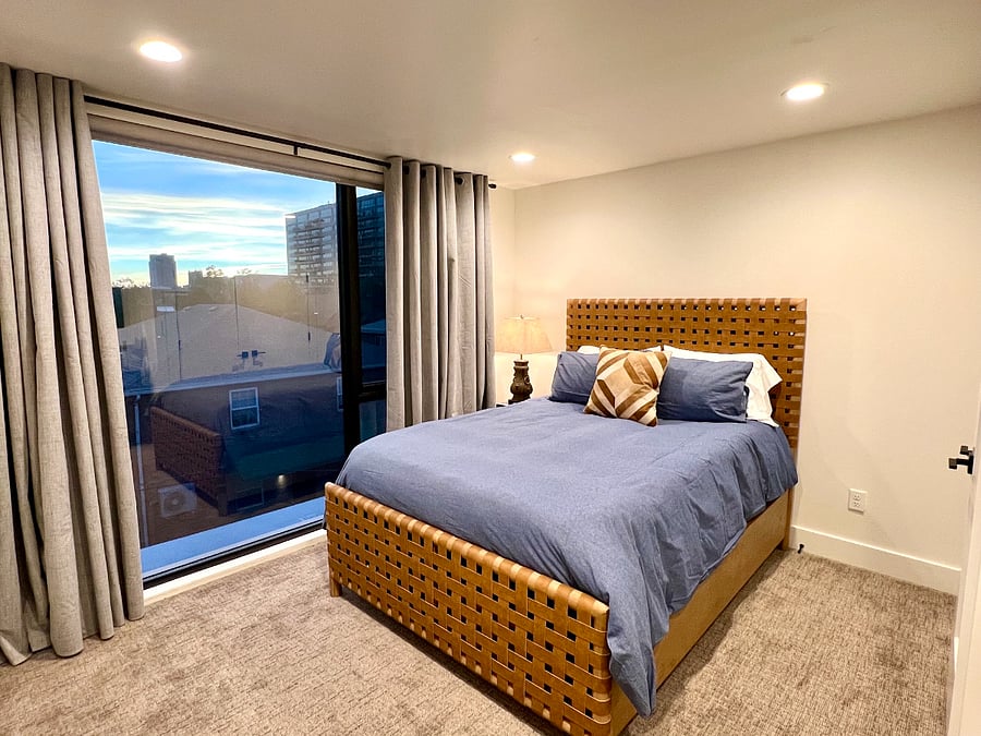 Fourth bedroom with queen size bed, closet, dresser and floor to ceiling windows with shades and blackout curtains.