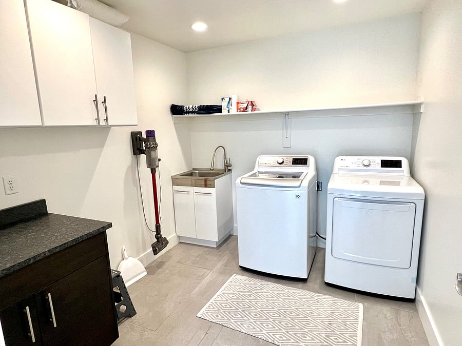 Full laundry room with new washer/dryer, sink, and plenty of storage with sheets, towels, vacuum, etc.
