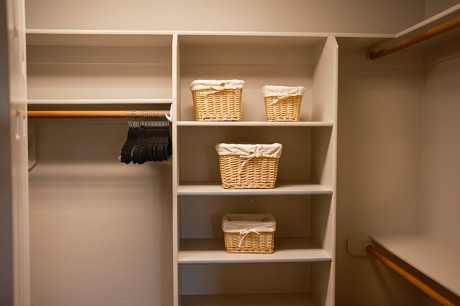 Large walk-in closet, more around the door to the left, baskets and a laundry hamper on the floor, lots of hangers