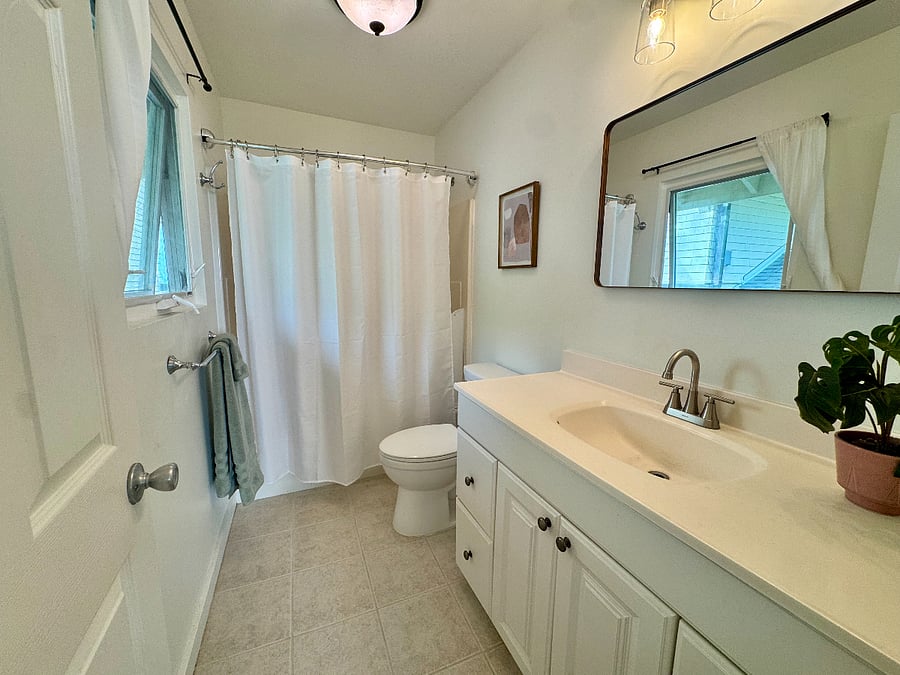 Full bathroom with tub/shower combo, full vanity, and a window for natural light and ventilation.