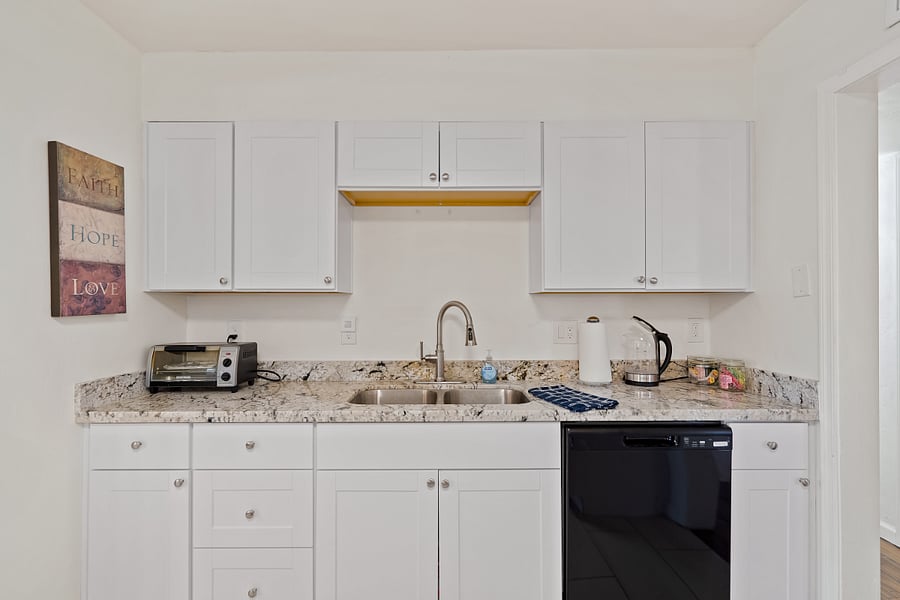 Kitchen sink area and dishwasher with tea area and Mr Coffee pot nearby. 