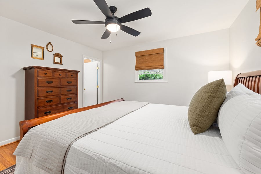 Primary bedroom with dresser and entrance to attached full bathroom