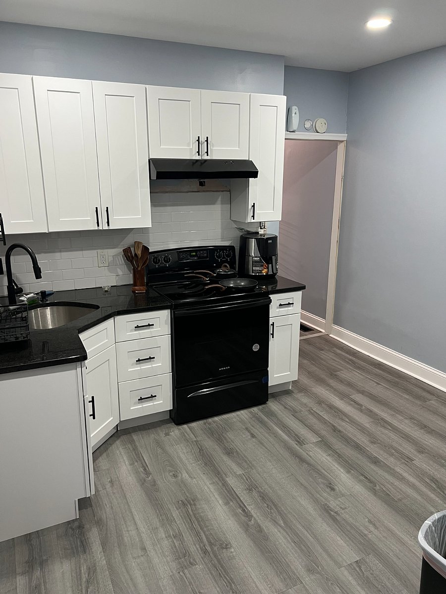 Modern kitchen with granite countertops, electric stove, air fryer, and stocked with pots, pans, and cooking essentials for a convenient, at-home experience