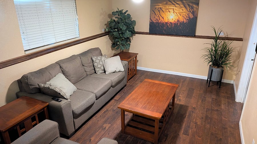 Living room #2 downstairs with sofa, chair, end tables, coffee table and TV. 