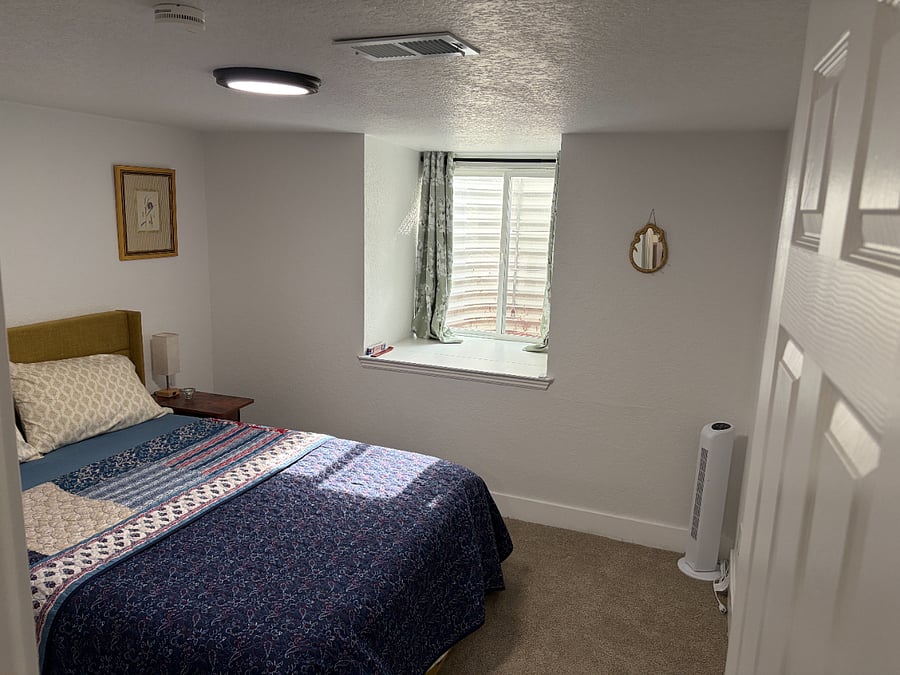 Queen sized bed with window to the front of the property [streetside] with two sidetables that include charging stations