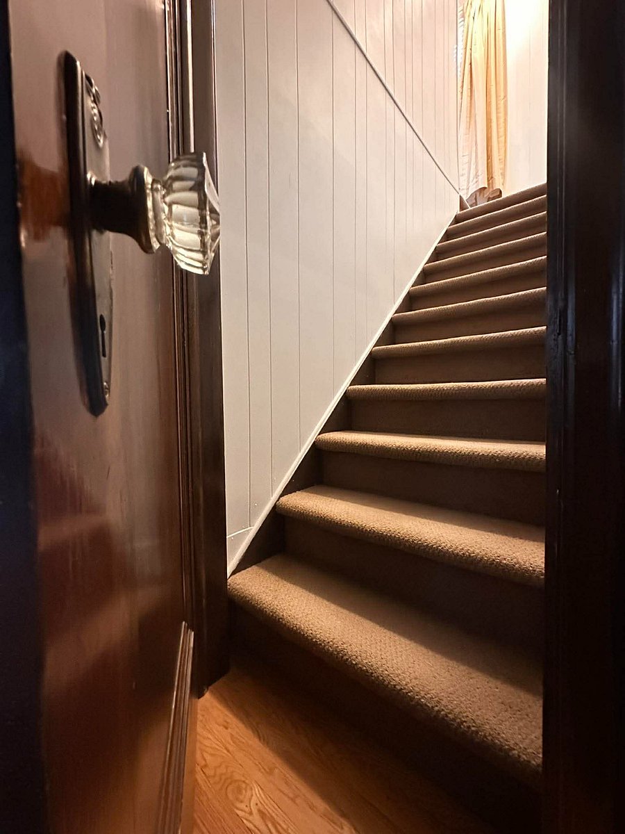 Stairwell to upper level to the remote work desk set up and gym quality treadmill with weights