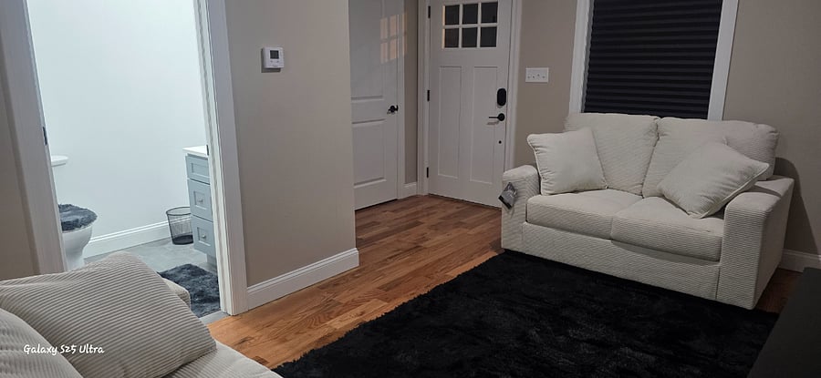 living room and front door entrance with half of bathroom and closet view