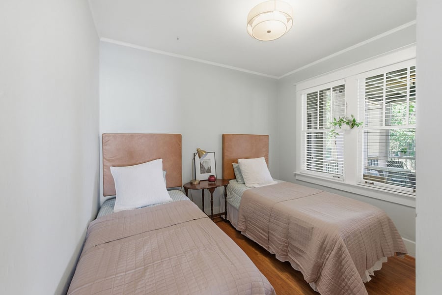 Main floor guest bedroom with two XL twin beds that can be pushed together to create a split king. Windows overlook the covered back porch. This room is full of cozy charm with original doors and hardware.