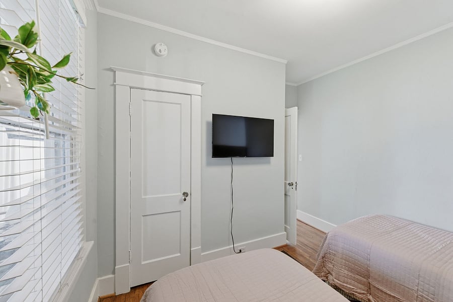 This main floor guest bedroom features a wall-mounted TV.
