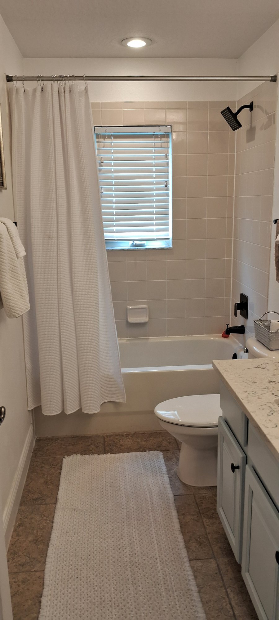 Across from the guestroom is the spacious guest bath w/tub and rainfall showerhead