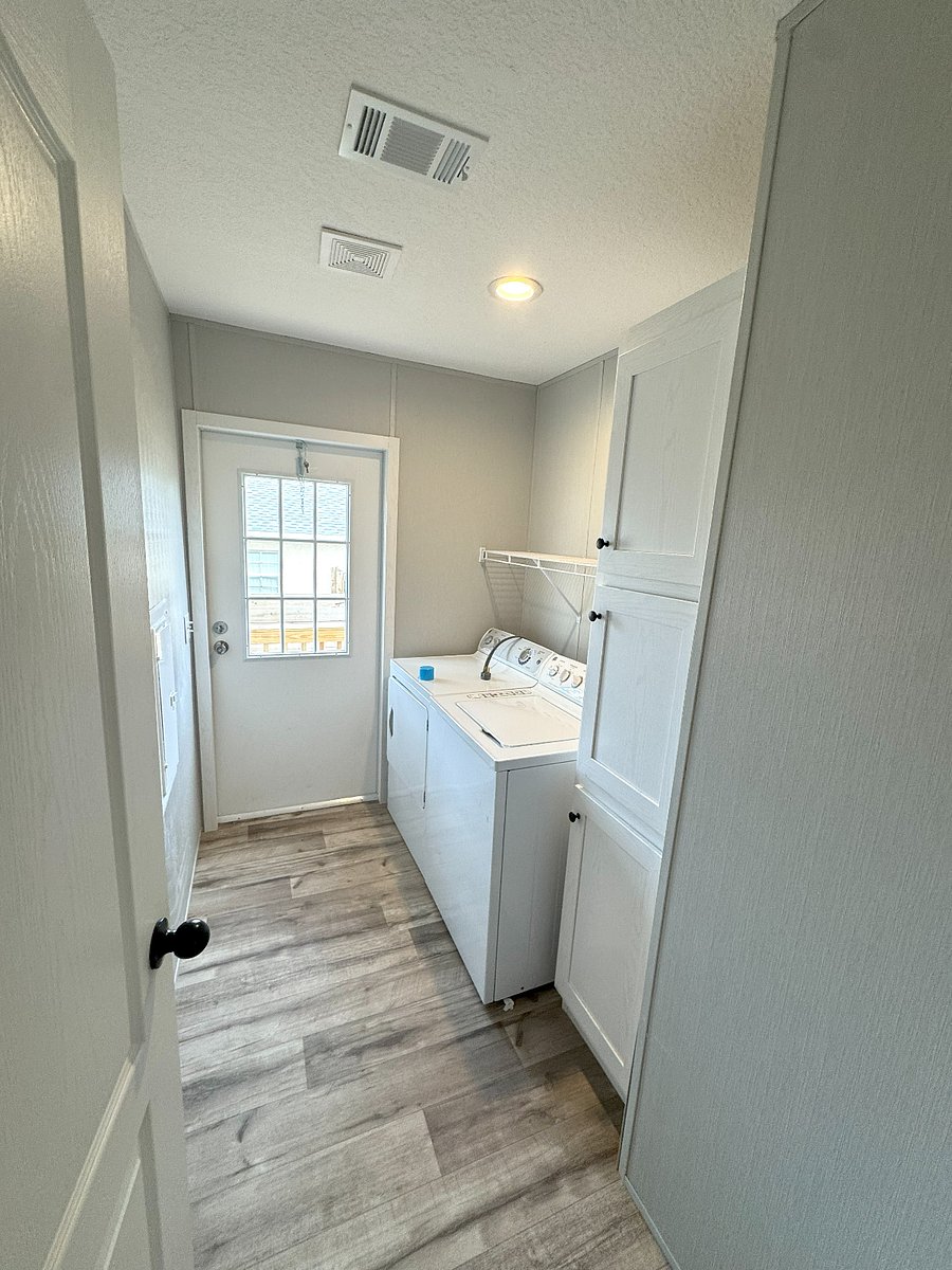 Laundry room with full sized washer & dryer, ironing board and linen closet.  With exterior side door.
