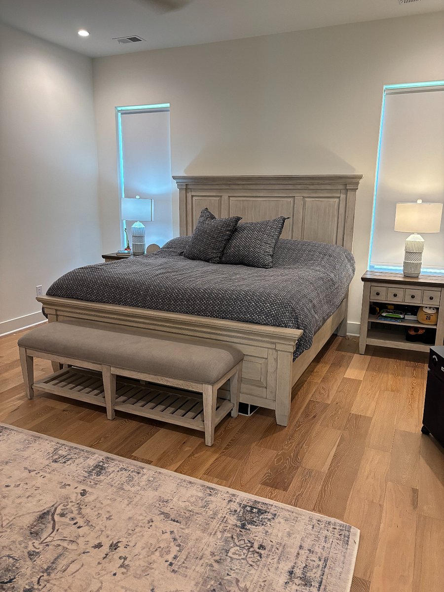 Spacious and relaxing master bedroom featuring a king-size bed, beautiful hardwood floors, soaring ceilings, and built-in Sonos speakers for a premium in-room experience. The perfect private retreat to unwind and recharge after a day exploring Nashville.