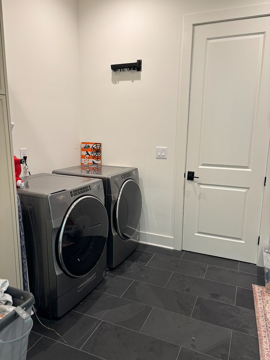 Spacious laundry room equipped with a full-size washer and dryer, along with adjacent hanging space and a utility sink for added convenience. Perfect for extended stays, families, or guests looking for the comforts of home during their time in Nashville.