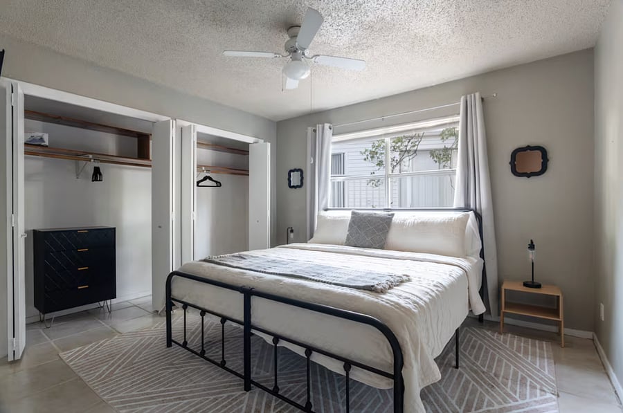 master bedroom - queen bed. black outshade, closet and small mounted TV