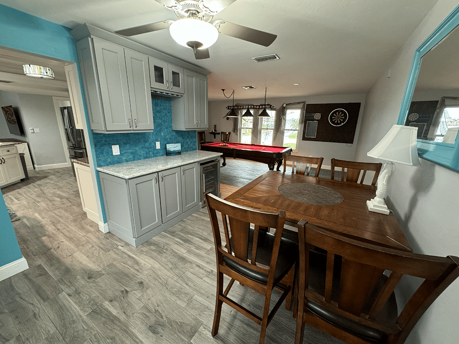Just outside of main bedroom, bar area with open pool table area, dining table and view of kitchen into living room
