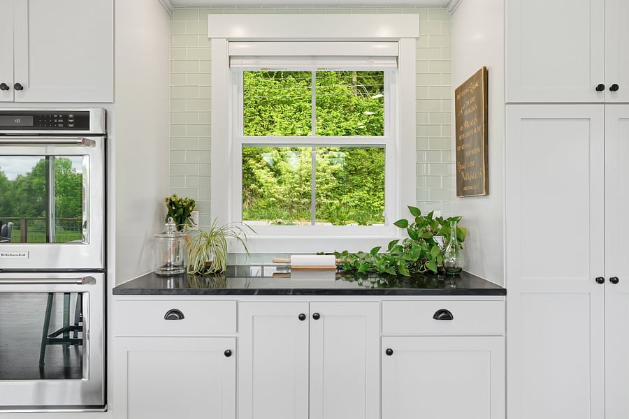 Baking station supplied with all baking-related items including professional Kitchenaid mixer on pull-out stand, double walll oven, large pantry cabinet, soapstone countertop, and overhead lighting.
