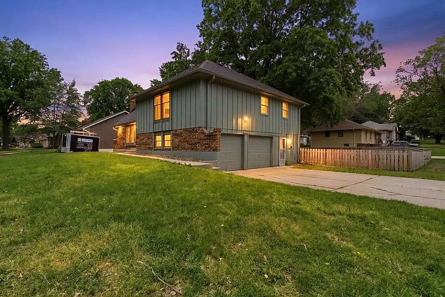 Beautiful twilight exterior showcasing the homes inviting curb appeal, spacious front yard, and peaceful neighborhood atmosphere perfect for relaxing stays near Kansas City.